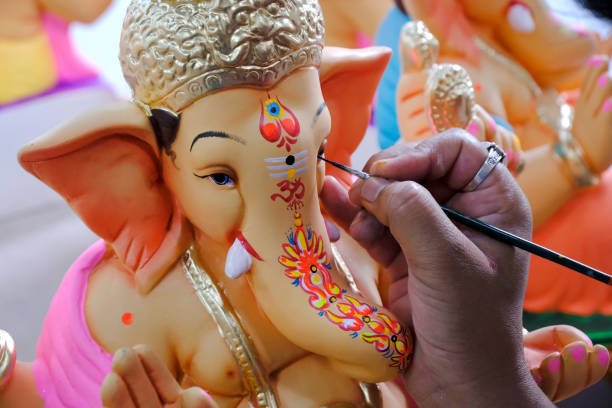 Artist painting and giving final touches to Lord Ganesha, ahead of Ganesha Chaturthi festival in Pune, Maharashtra, India.